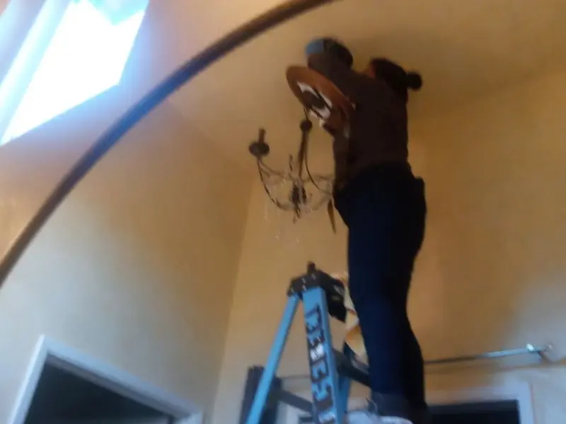 Electrician installing a chandelier in a Cache residence